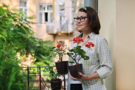 Beautiful Mature Woman With Potted Red Summer Flowers
