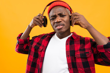 close-up of a black american man taking off his headphones on a yellow studio background