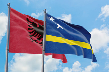 Curacao and Albania flags waving in the wind against white cloudy blue sky together. Diplomacy concept, international relations.