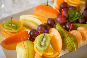 fresh fruit on a plate sliced kiwi grapes persimmon orange pear apple banana