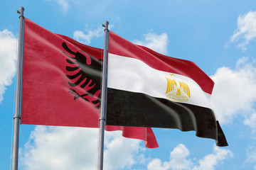 Egypt and Albania flags waving in the wind against white cloudy blue sky together. Diplomacy concept, international relations.