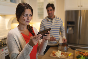 Young couple using tablet computer while cooking