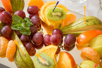fresh fruit on a plate sliced kiwi grapes persimmon orange pear apple banana