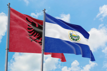 El Salvador and Albania flags waving in the wind against white cloudy blue sky together. Diplomacy concept, international relations.