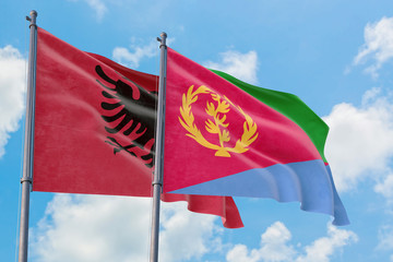 Eritrea and Albania flags waving in the wind against white cloudy blue sky together. Diplomacy concept, international relations.