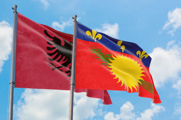 Guadeloupe and Albania flags waving in the wind against white cloudy blue sky together. Diplomacy concept, international relations.