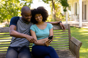 Happy young couple sitting on a bench in the garden