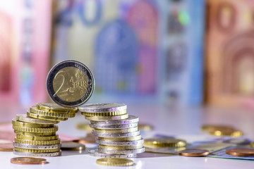 Stapel Euro-Münzen mit stehender 2-EURO-Münze aus 2 Euro, 1 Euro und Cent-Münzen mit einem...