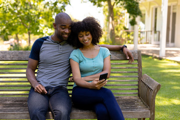 Happy young couple sitting on a bench in the garden
