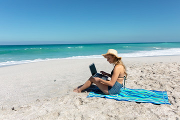 Young woman with computer at the beach