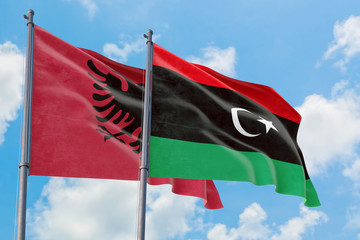 Libya and Albania flags waving in the wind against white cloudy blue sky together. Diplomacy concept, international relations.