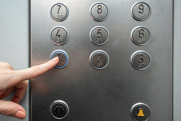 Female hand, finger presses the elevator button. up the career ladder.