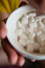 Marshmallow in cocoa is enjoyed by a man holding in his hands.