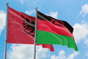 Malawi and Albania flags waving in the wind against white cloudy blue sky together. Diplomacy concept, international relations.