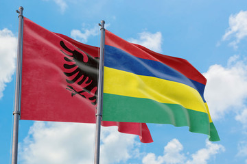Mauritius and Albania flags waving in the wind against white cloudy blue sky together. Diplomacy concept, international relations.