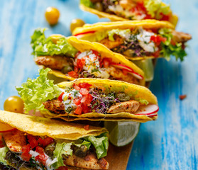 Tacos, corn tortilla tacos with grilled chicken meat and fresh vegetables with addition aromatic and spicy herb sauce, close-up. Traditional Mexican dish