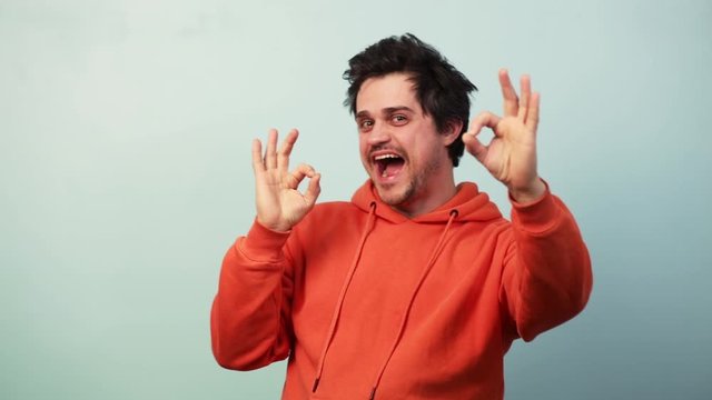 Guy show approval gesture on blue background