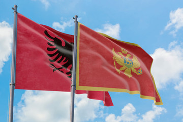 Montenegro and Albania flags waving in the wind against white cloudy blue sky together. Diplomacy concept, international relations.