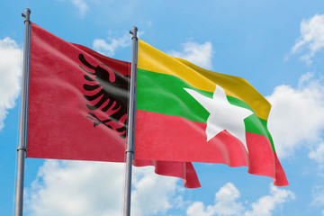 Myanmar and Albania flags waving in the wind against white cloudy blue sky together. Diplomacy concept, international relations.