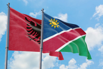 Namibia and Albania flags waving in the wind against white cloudy blue sky together. Diplomacy concept, international relations.