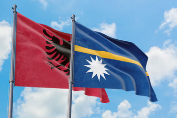 Nauru and Albania flags waving in the wind against white cloudy blue sky together. Diplomacy concept, international relations.