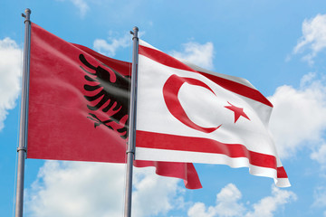 Northern Cyprus and Albania flags waving in the wind against white cloudy blue sky together. Diplomacy concept, international relations.