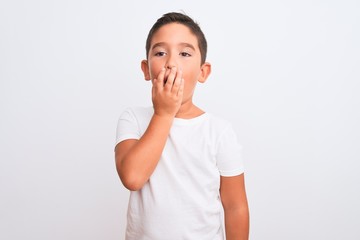 Beautiful kid boy wearing casual t-shirt standing over isolated white background bored yawning tired covering mouth with hand. Restless and sleepiness.