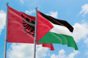 Palestine and Albania flags waving in the wind against white cloudy blue sky together. Diplomacy concept, international relations.