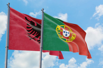 Portugal and Albania flags waving in the wind against white cloudy blue sky together. Diplomacy concept, international relations.