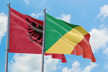 Republic Of The Congo and Albania flags waving in the wind against white cloudy blue sky together. Diplomacy concept, international relations.