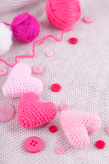 Knitted pink hearts, knit threads, buttons on a knitted gray background. Needlework, handmade, hobbies, DIY. Valentines day
