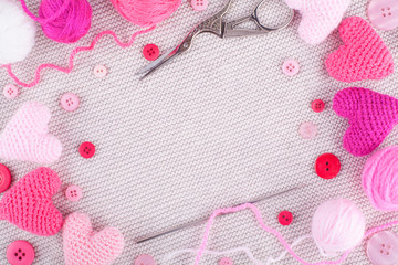 Knitted pink hearts, knit threads, buttons on a knitted gray background. Needlework, handmade, hobbies, DIY. Valentines day