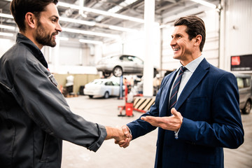 Smiling mechanic and his customer shaking hands
