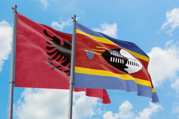 Swaziland and Albania flags waving in the wind against white cloudy blue sky together. Diplomacy concept, international relations.