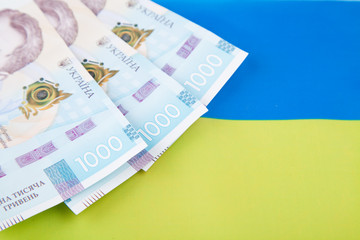Ukrainian hryvnia, several banknotes of 1000 hryvnia against the background of the flag of Ukraine. Financial background from Ukrainian banknotes. Money. Close-up