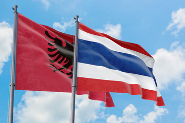 Thailand and Albania flags waving in the wind against white cloudy blue sky together. Diplomacy concept, international relations.