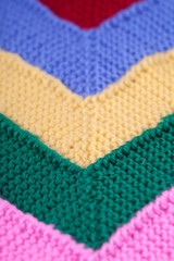Colored plaid from different yarns. Knitted texture, woolen product, homework, hobbies, knitting, needlework. Close-up, background.