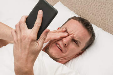 Annoying smartphone. Wake up call. Spam messaging. Disturbed sleeping man.