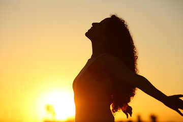 Silhouette of a lady breathing fresh air at sunset