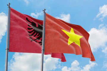 Vietnam and Albania flags waving in the wind against white cloudy blue sky together. Diplomacy concept, international relations.