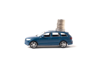 Blue toy iron car with coins on a white background. concept of earnings, income and high cost