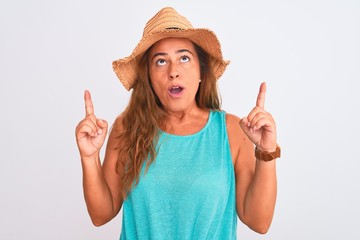 Middle age mature woman wearing summer hat over white isolated background amazed and surprised...