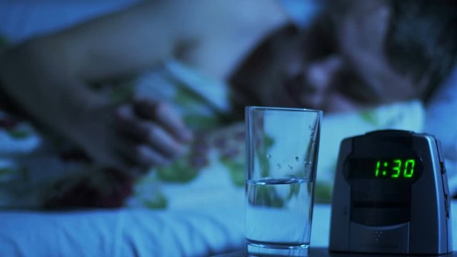 A man drinks sedative or sleeping pills at night in bed