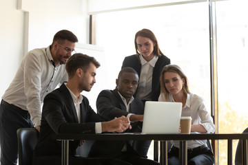 African team leader showing application help to workmates using laptop