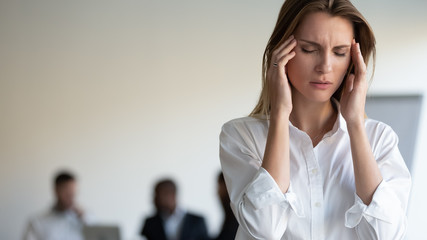 Woman touches temples suffers from headache by stress in workplace