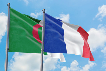 France and Algeria flags waving in the wind against white cloudy blue sky together. Diplomacy concept, international relations.