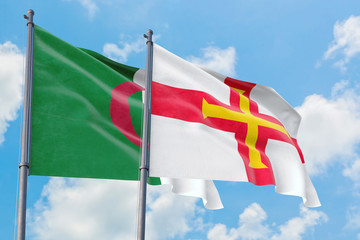 Guernsey and Algeria flags waving in the wind against white cloudy blue sky together. Diplomacy concept, international relations.
