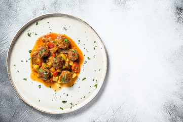 Beef meatballs with tomato sauce and vegetables in a pan. Gray background. Top view. Space for text