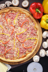 Delicious pizza. Large meat pizza with bacon, sausage, salami, pepperoni and olives. Homemade delicious italian pizza on wooden table for dinner. Italian cuisine.
