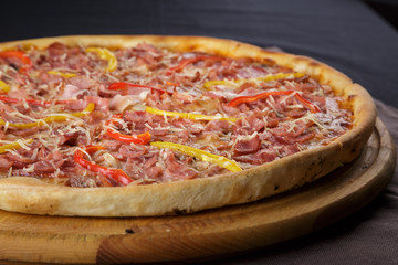 Delicious pizza. Large meat pizza with bacon, sausage, salami, pepperoni and olives. Homemade delicious italian pizza on wooden table for dinner. Italian cuisine.